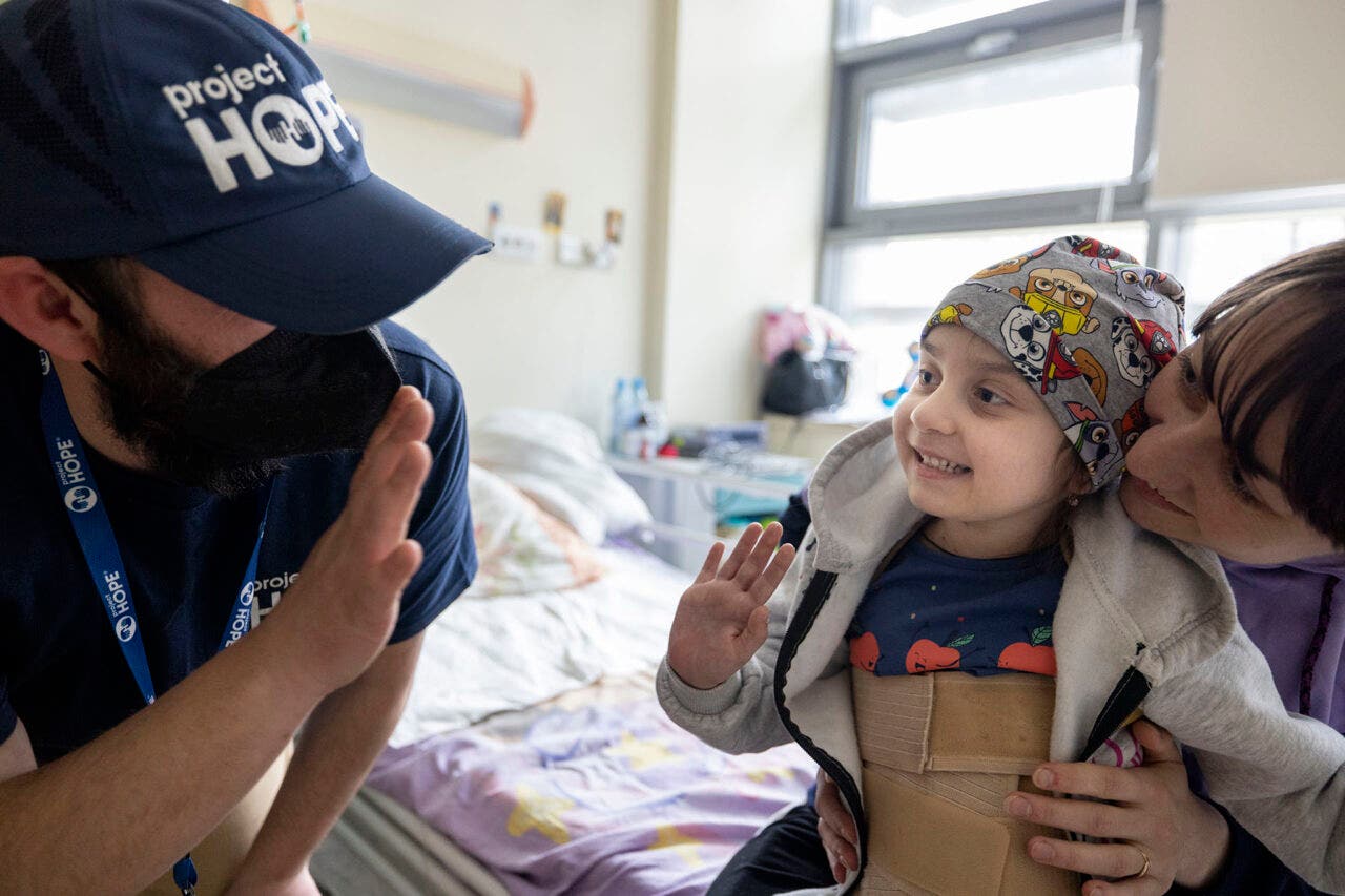 Project HOPE member waving to woman and smiling 5-year-old patient at University Children’s Hospital in Krakow.