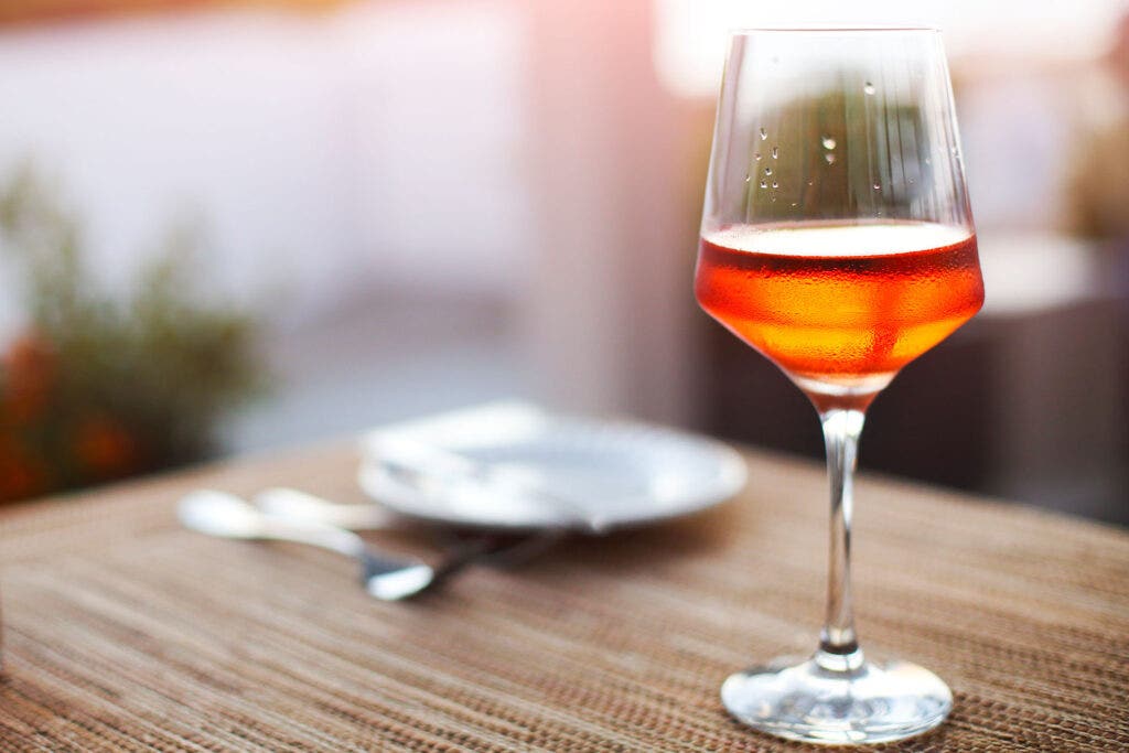 Glass of orange wine sitting on table