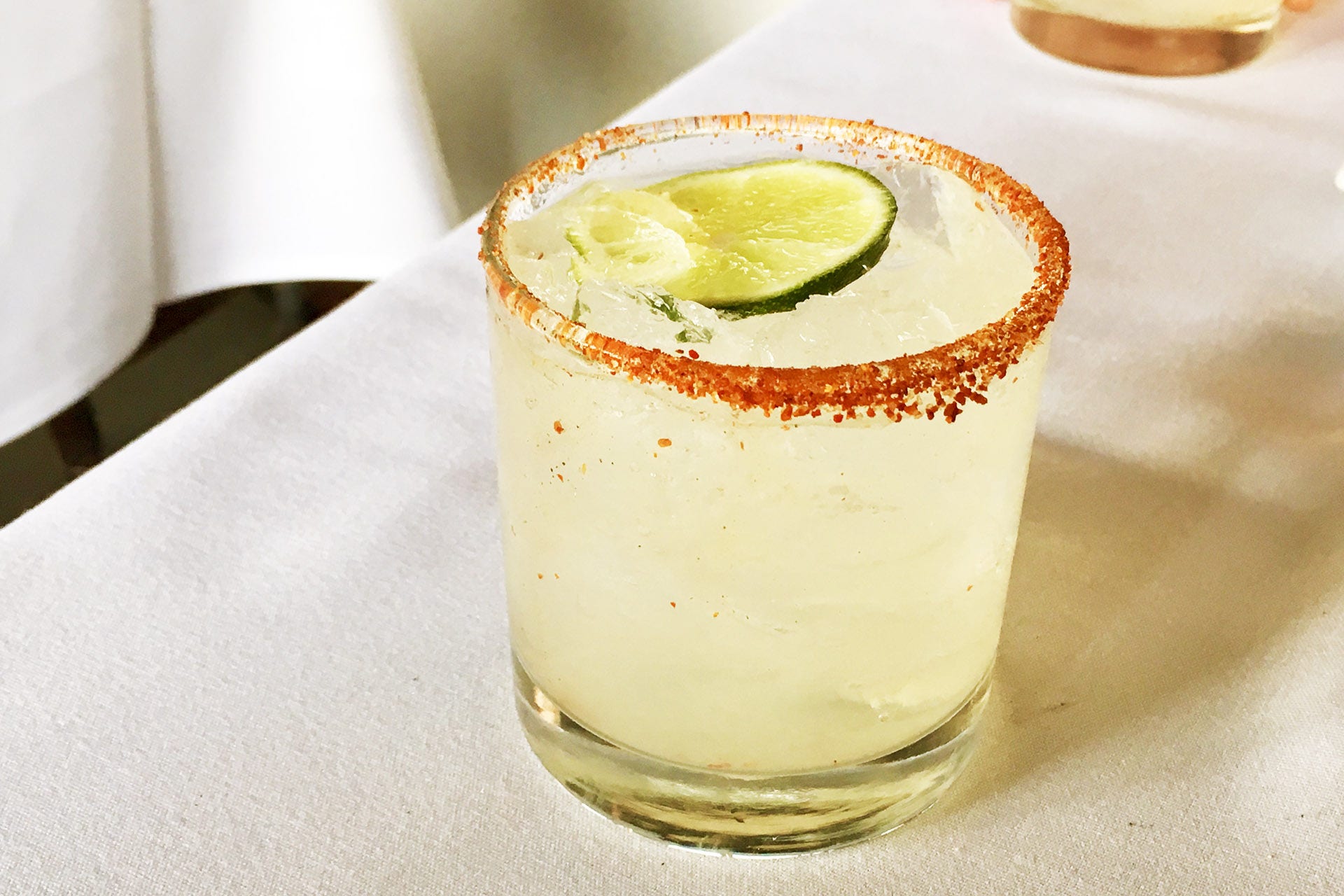 Chili-Salt Rimmed Paloma Cocktail on White Tablecloth