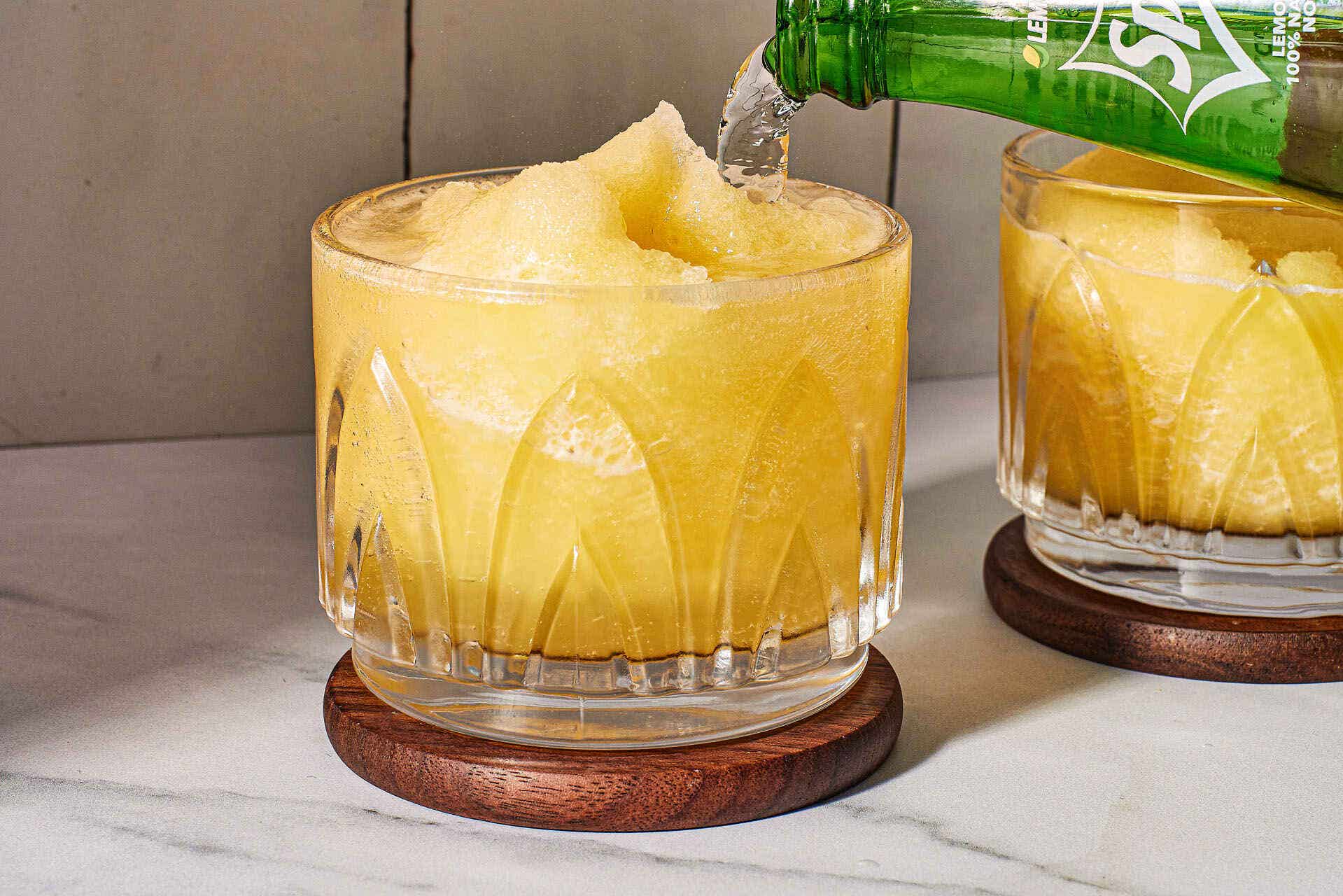 Action shot of pouring white soda into a glass with two scoops of slush mixture in it. Include ingredients in the same shot and shoot at eyelevel