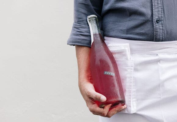 Close up on someone holding a bottle of natural wine